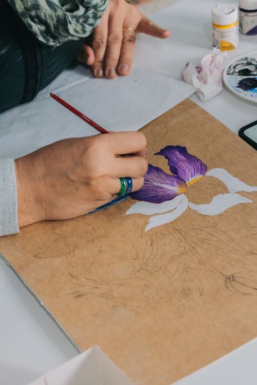 Free An artist's hand painting a purple iris flower on canvas, detailed brush technique. Stock Photo