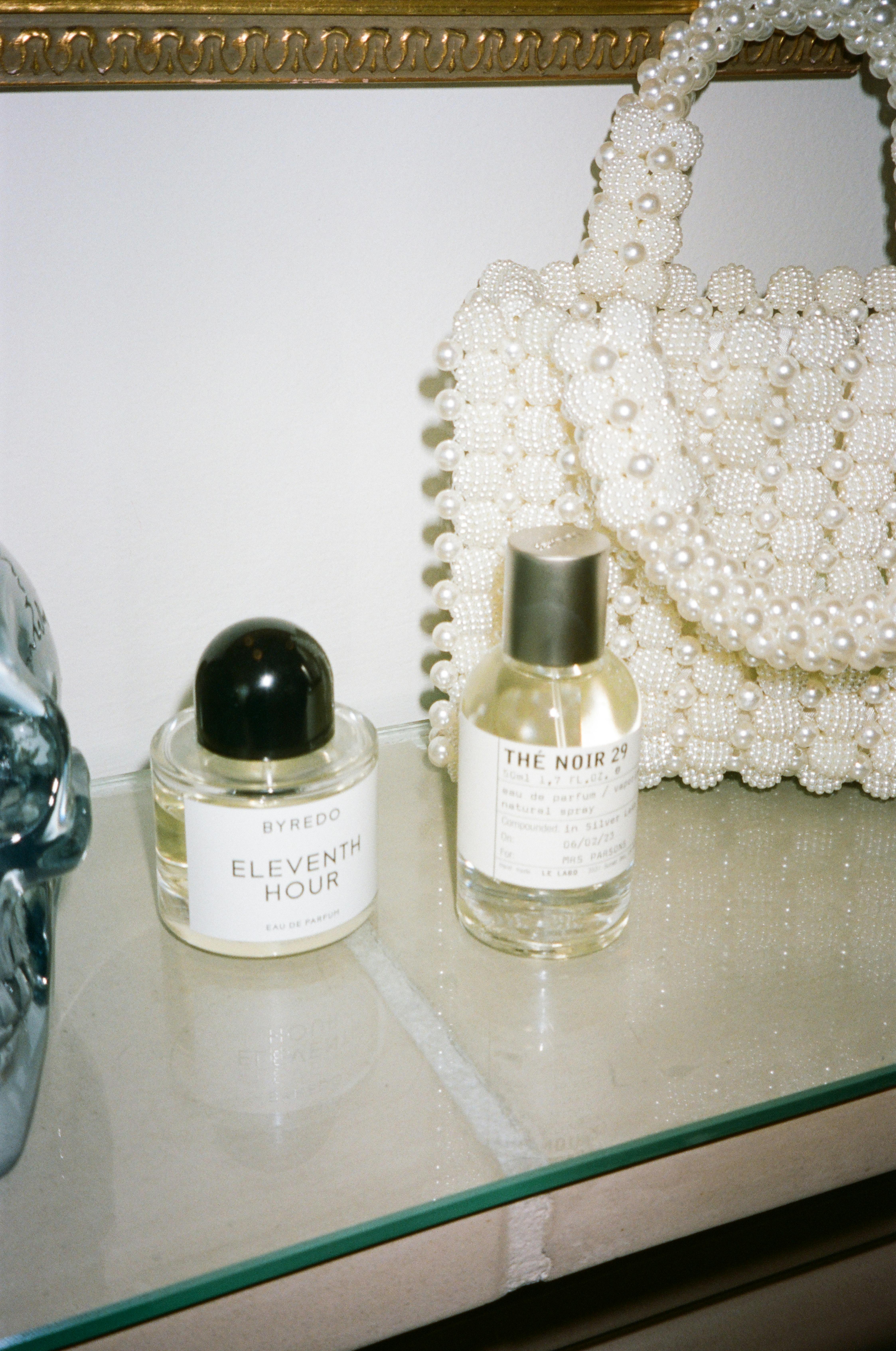 Elegant display of Byredo and Le Labo perfumes with a pearl handbag.