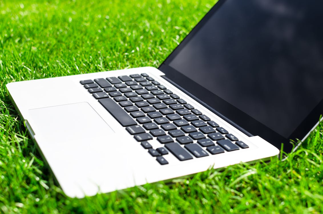 бесплатная Macbook Pro с выключенным экраном на траве Стоковое фото