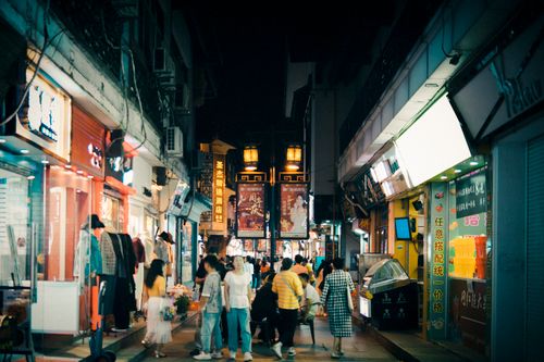 Free Vibrant night scene of people exploring an illuminated urban alley market. Stock Photo