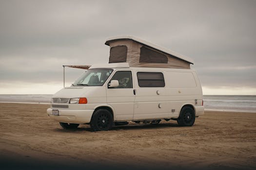 A classic Volkswagen camper van parked on the sandy shore of Oceano Beach, California.