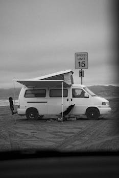 Black and white photo of a vintage camper van at Oceano Dunes, California.