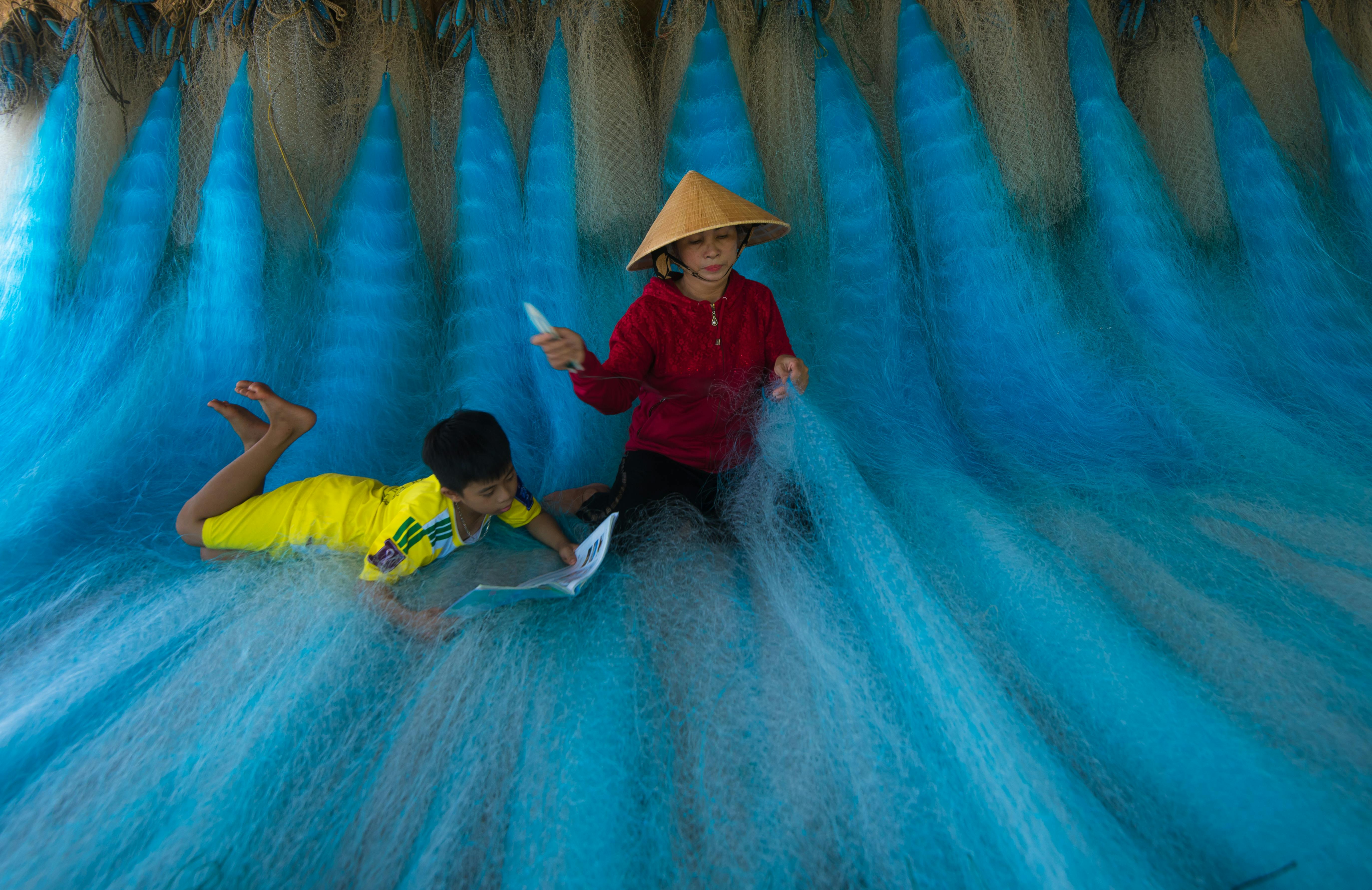 Two children engaged with blue fishing nets, showcasing traditional activities and play.