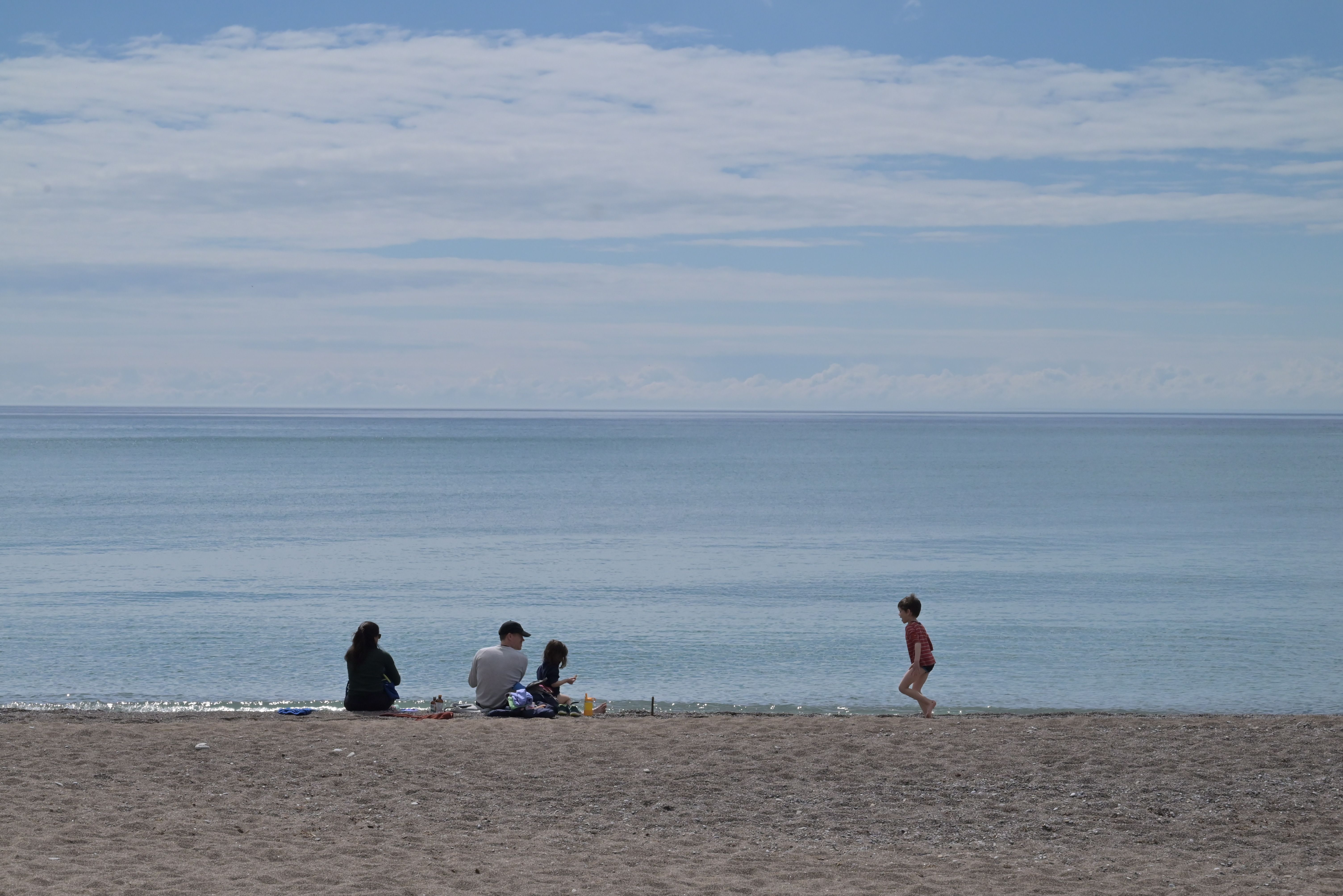 A family on a quiet beach under a clear sky.
