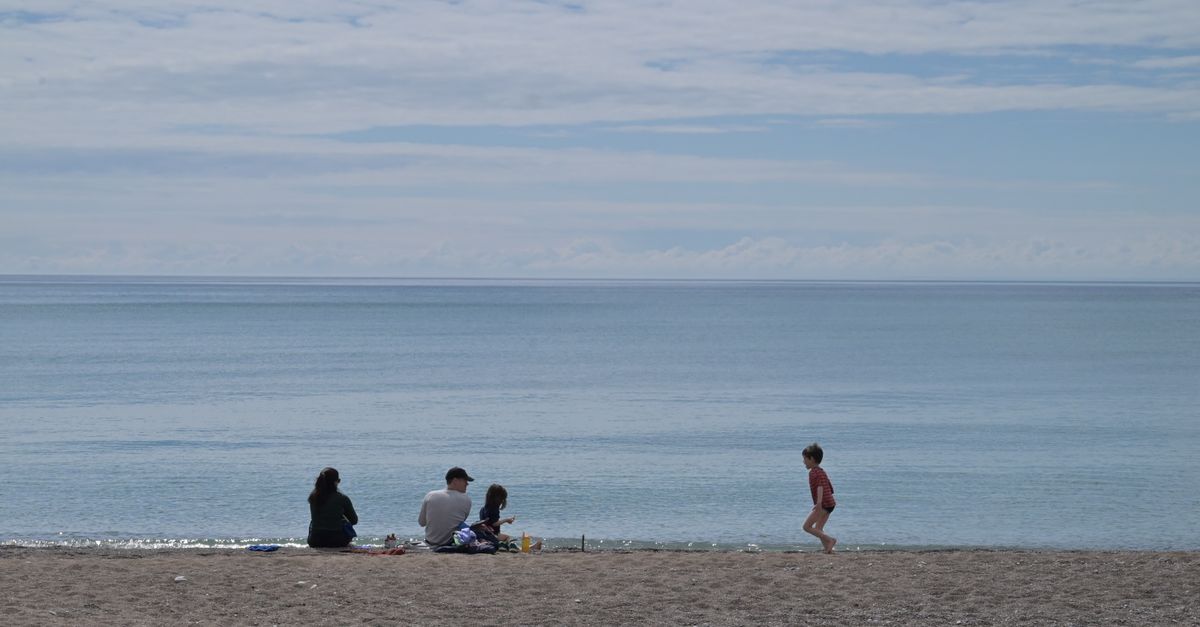 A family on a quiet beach under a clear sky.