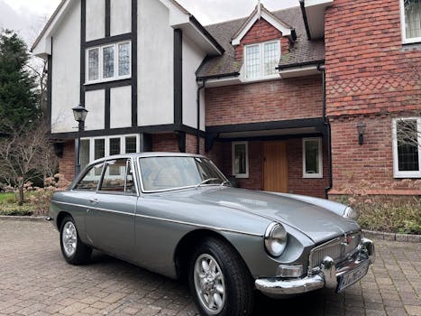A vintage silver MG car parked outside a charming Tudor-style house in Ascot, UK.