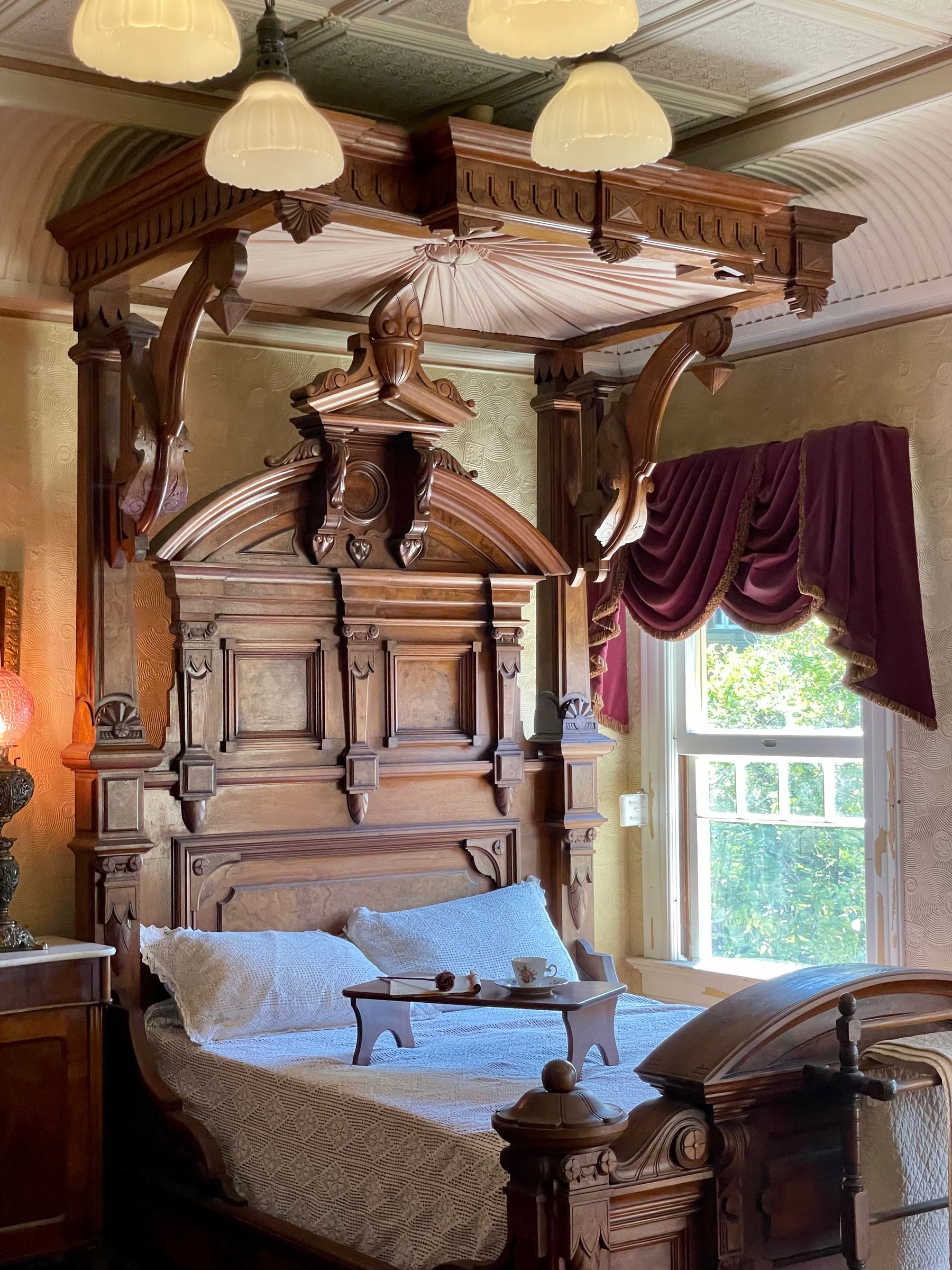 Layered Victorian room with dark wood furniture, patterned textiles, decorative trim and warm filtered light