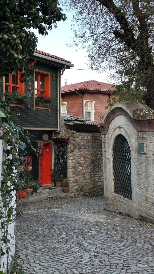 Free A quaint historic street featuring stone walls, red doors, and classic houses on a cobblestone path. Stock Photo