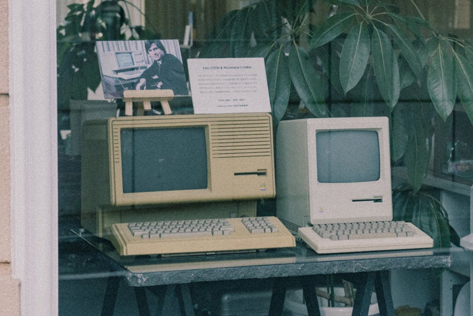 Computadores Apple retrô com teclados expostos na vitrine de uma loja em Tóquio, exibindo o design tecnológico inicial.