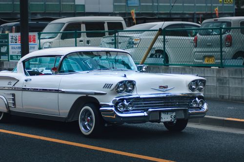 Free A vintage white car parked in an urban setting, showcasing classic automotive style. Stock Photo