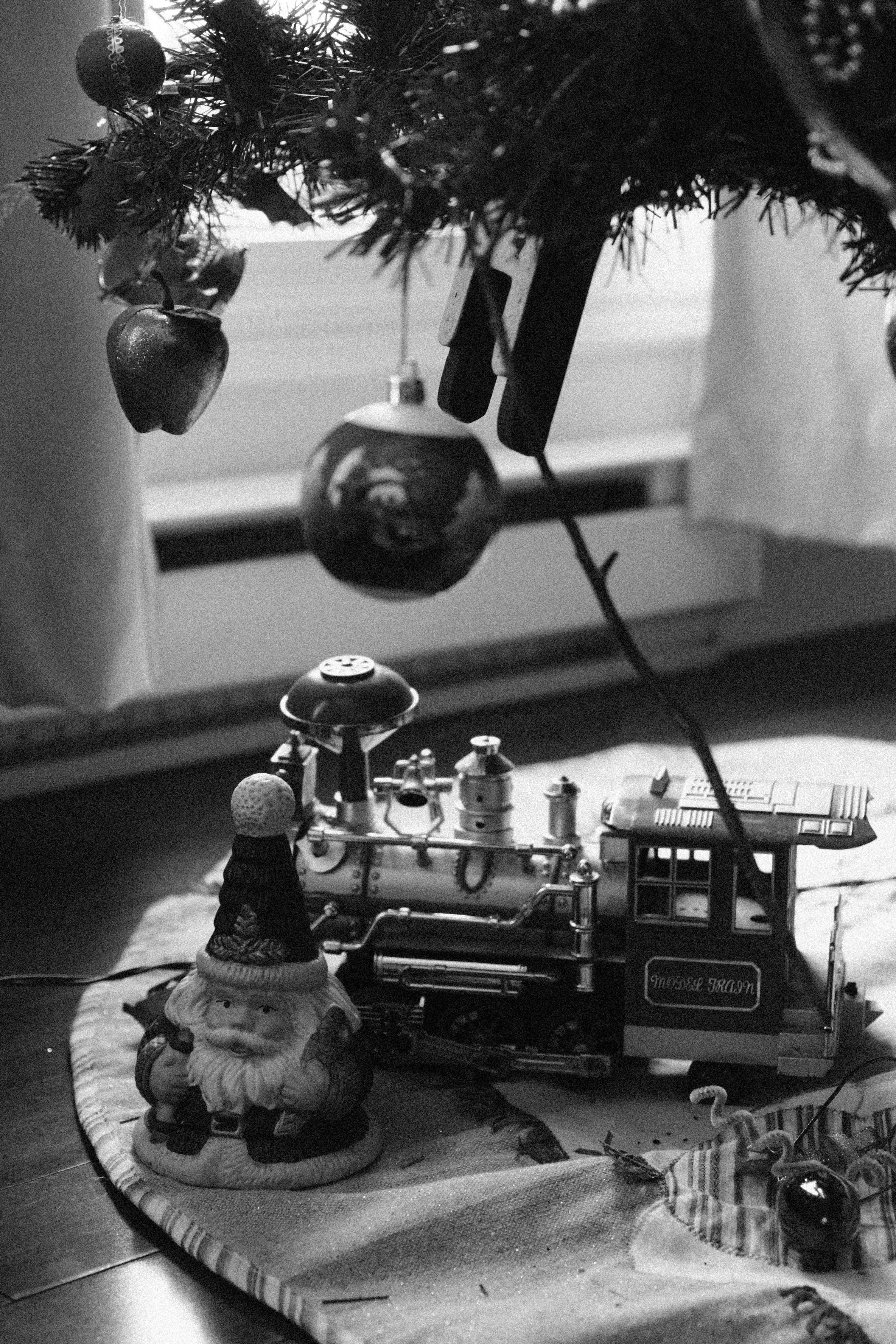 Festive Christmas tree base featuring classic toy train and decorations in black and white.
