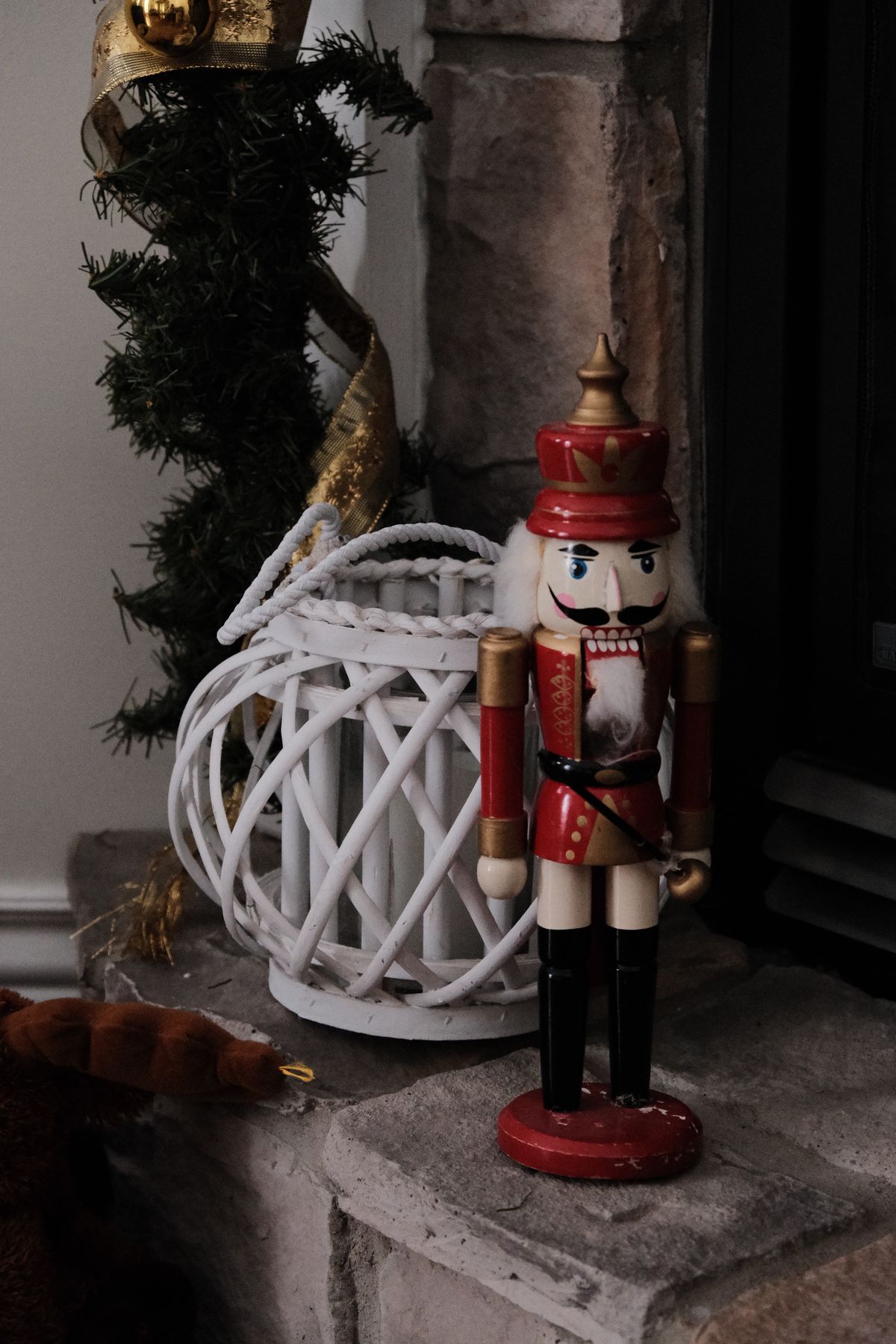 Traditional nutcracker beside a white lantern and garland by a fireplace