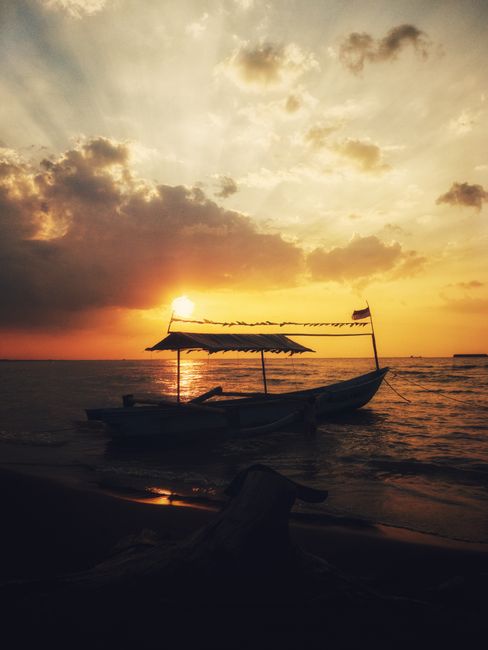 Scenic view of a silhouetted boat against a stunning orange sunset on a peaceful beach.