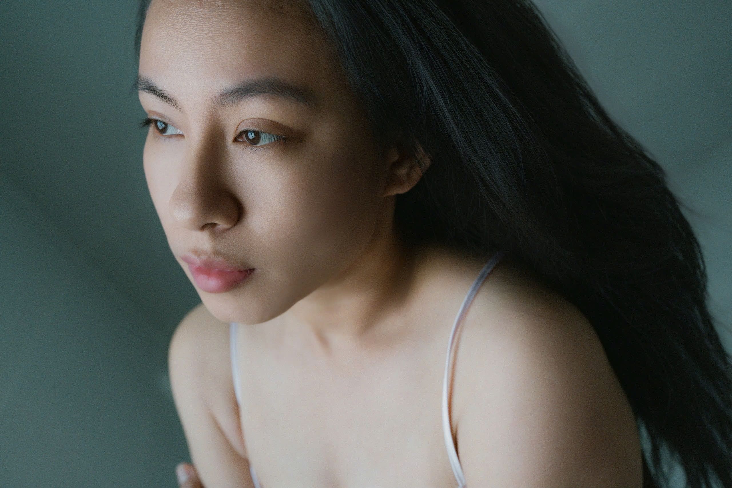 Reflective portrait of a young woman with soft light and natural expression.