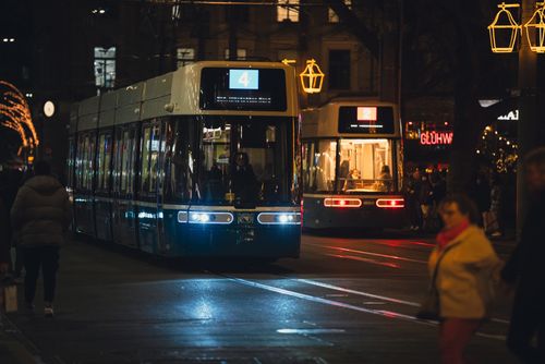 Free Illuminated trams at night with people on a bustling city street. Stock Photo