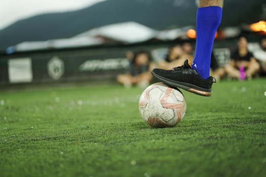 Soccer player in blue socks prepares to kick ball on green field. Sporty action moment.