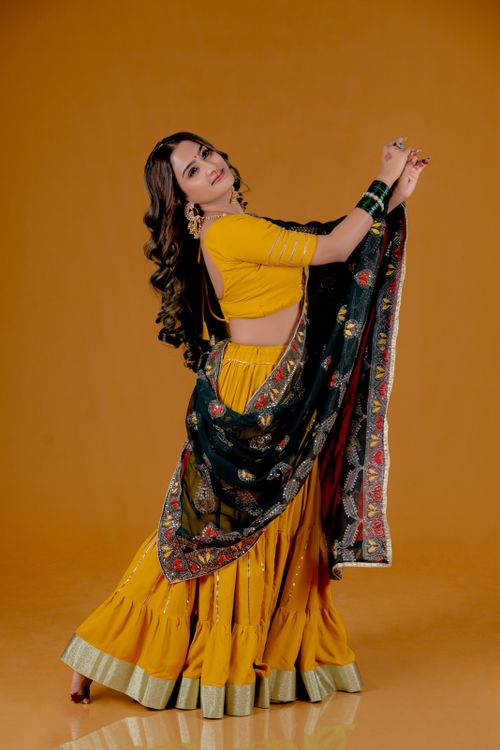 Free Woman in colorful traditional Indian dress performing dance on a warm, vibrant backdrop. Stock Photo