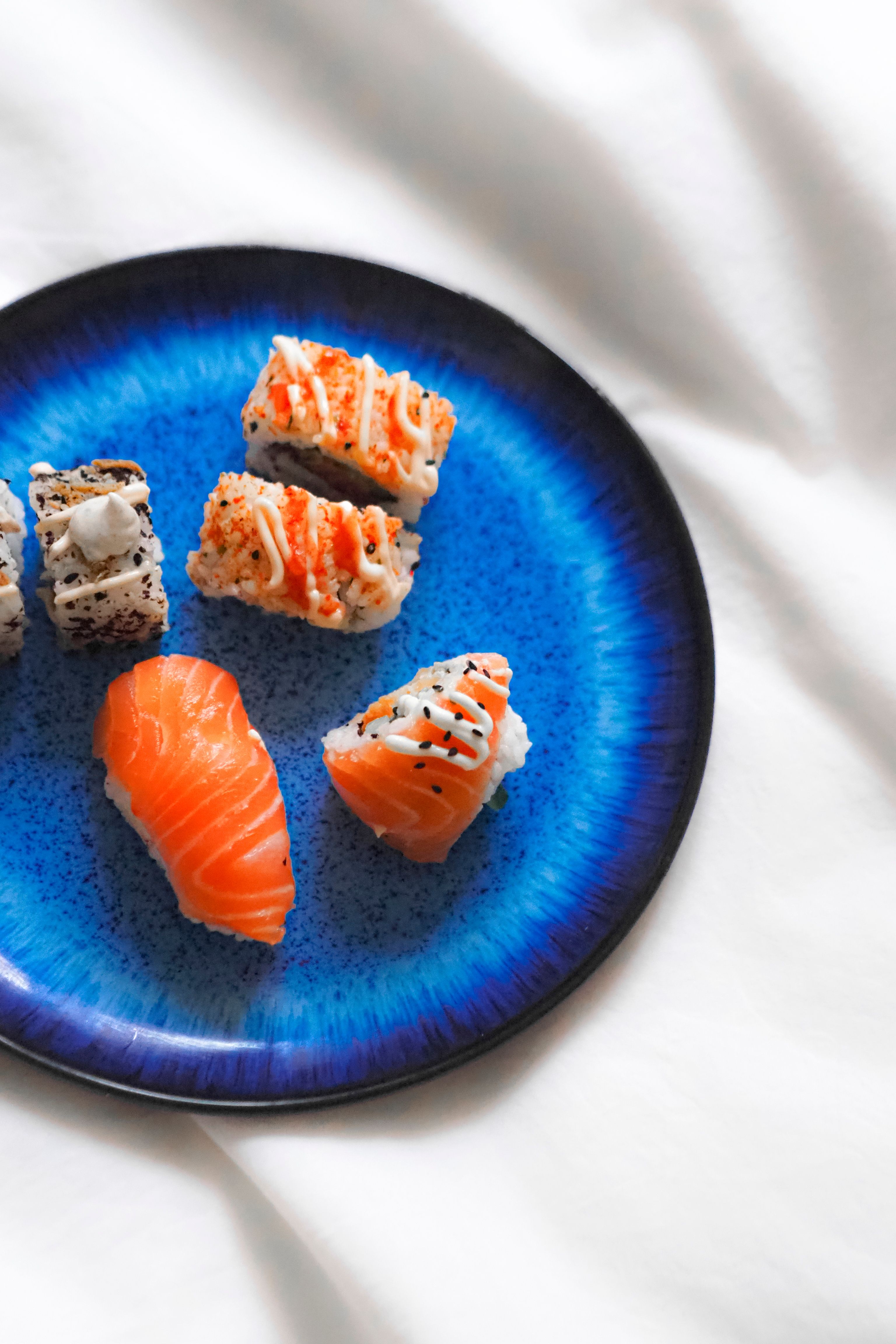 A vibrant display of sushi nigiri and rolls on a deep blue plate, showcasing gourmet Japanese cuisine.