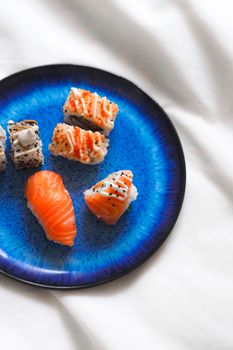 A vibrant display of sushi nigiri and rolls on a deep blue plate, showcasing gourmet Japanese cuisine.