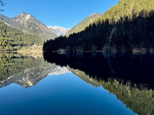 Free Tranquil mountain landscape with perfect lake reflection under a clear blue sky. Stock Photo