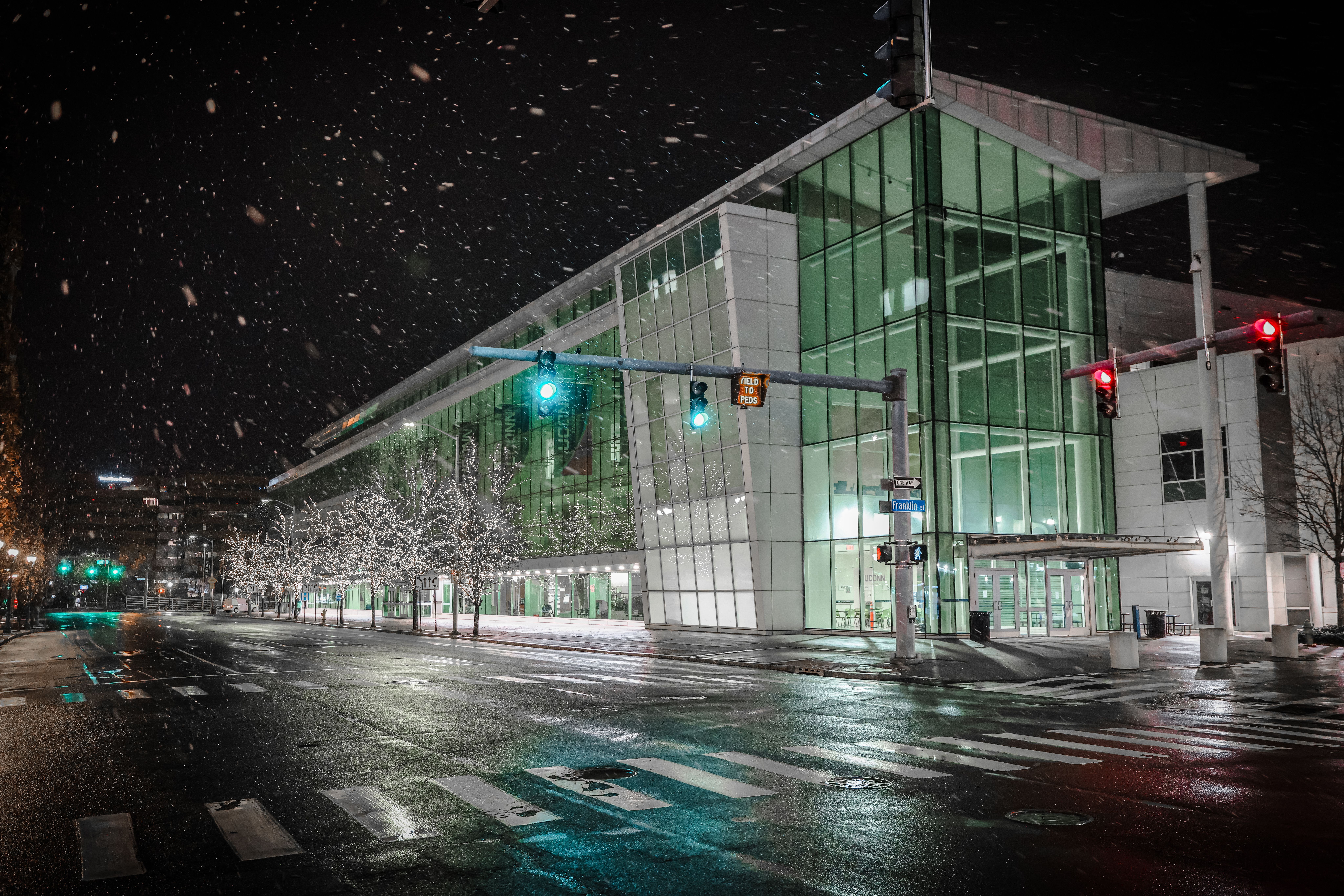 Modern glass building in downtown Stamford during a snowy winter night.