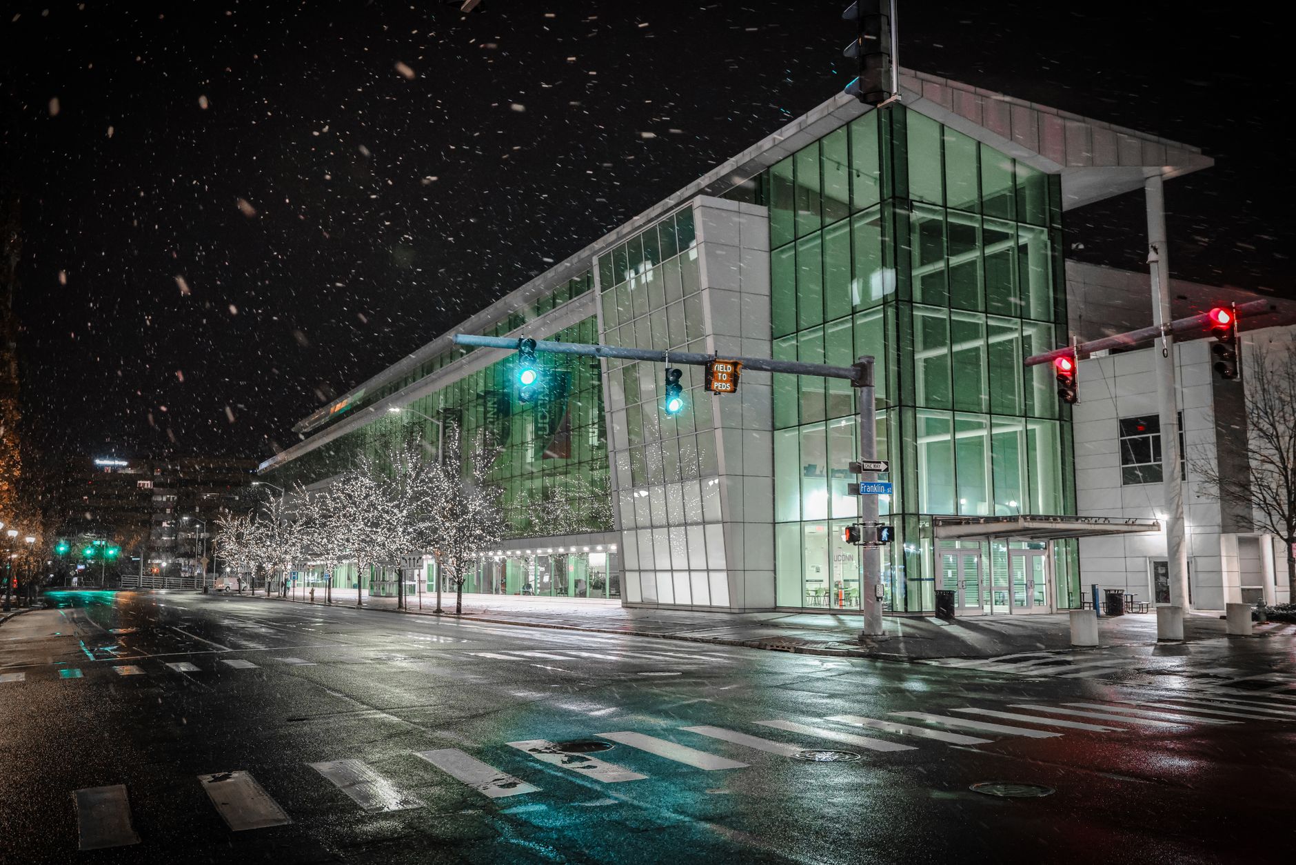 Modern glass building in downtown Stamford during a snowy winter night.