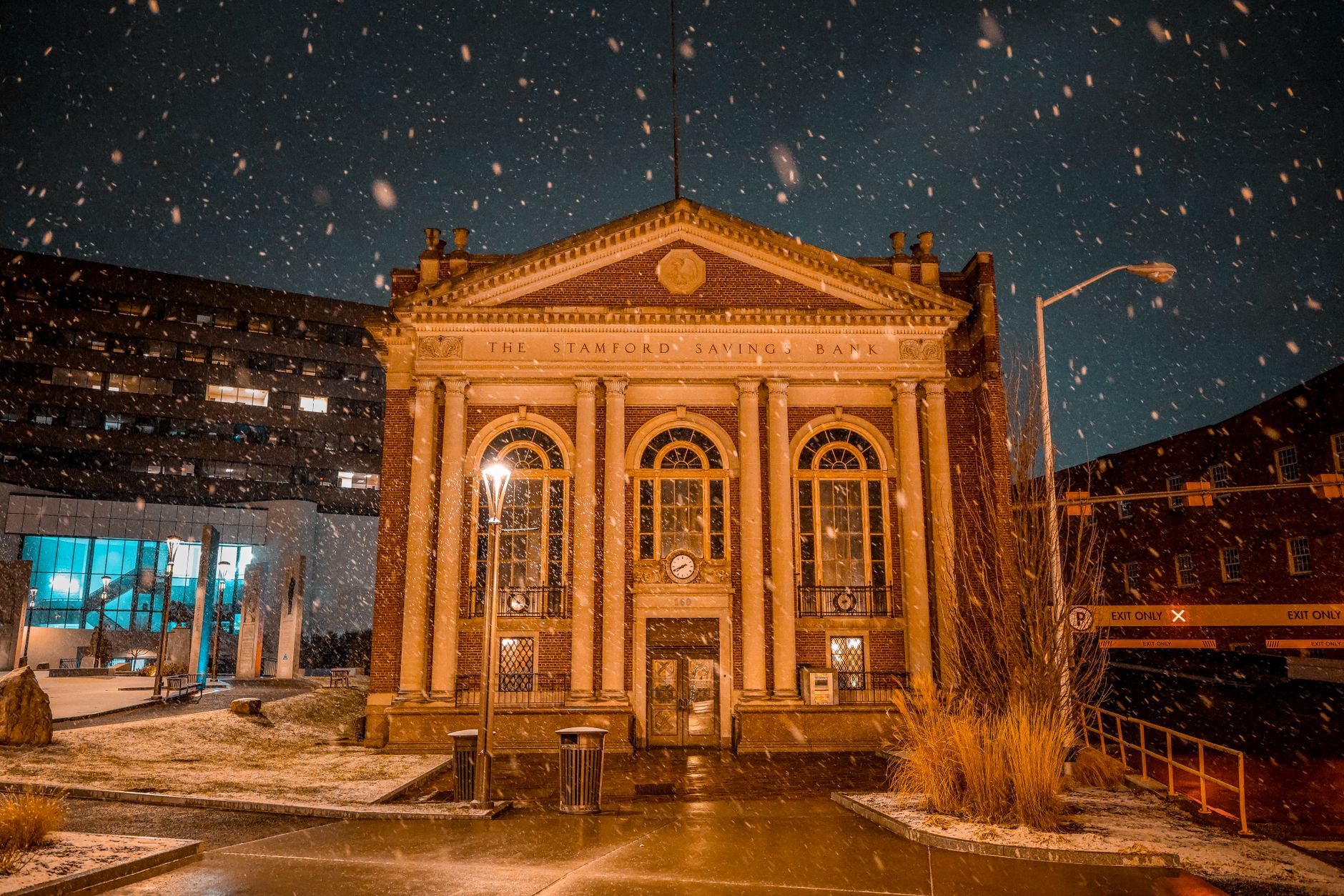 Historic Stamford Savings Bank illuminated at night during a snowfall in Stamford, Connecticut.