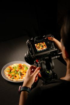 Photographer capturing a gourmet pizza in a professional studio setting.