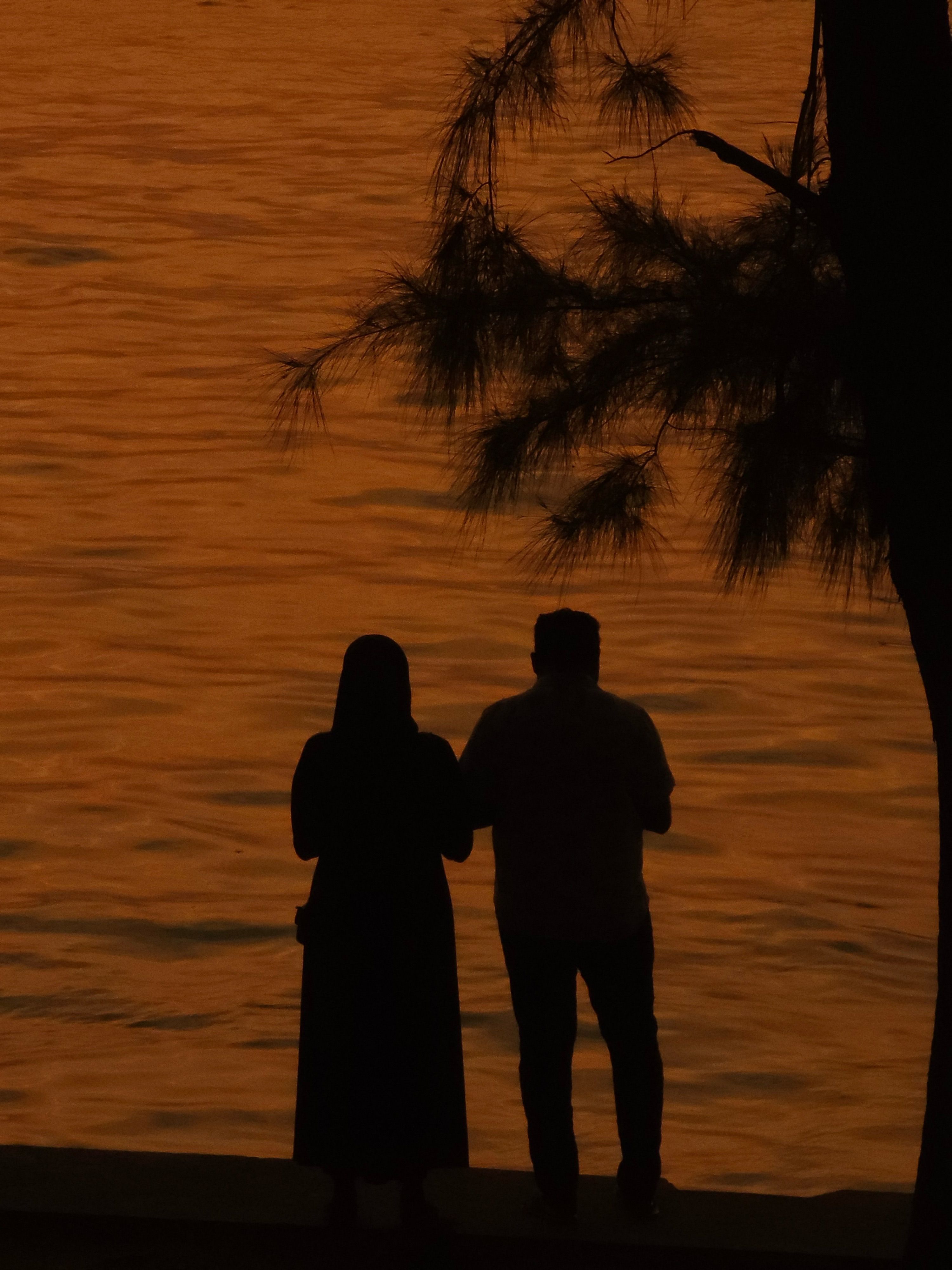 Silhouetted Couple by Tranquil Sunset Waters · Free Stock Photo