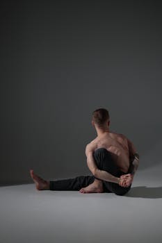 Tattooed man in a yoga pose indoors showing strength and flexibility.
