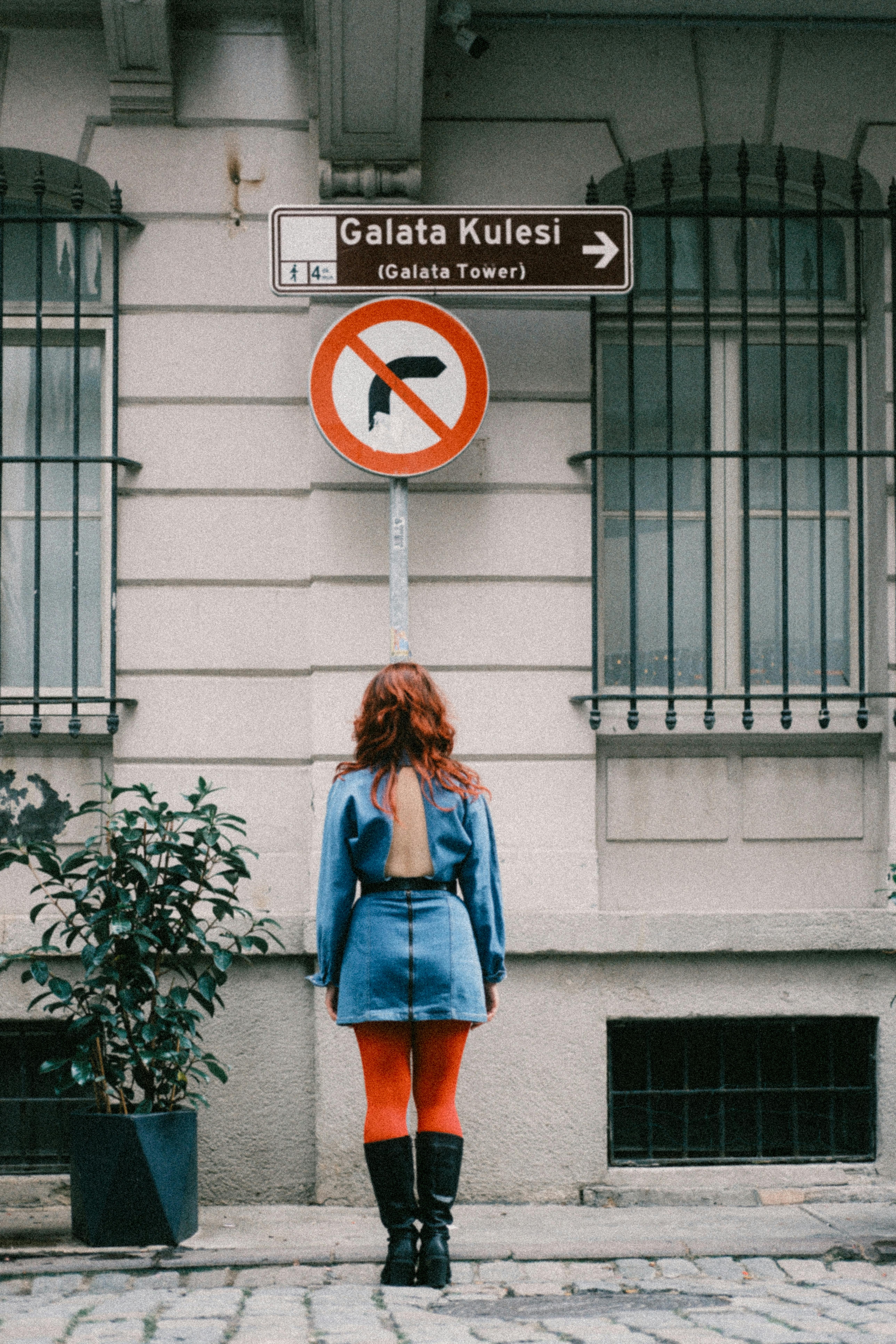 Woman in vibrant fashion under Galata Tower sign, urban Istanbul vibe.