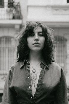 Black and white portrait of a young woman in an urban outdoor setting. Moody and artistic vibe.
