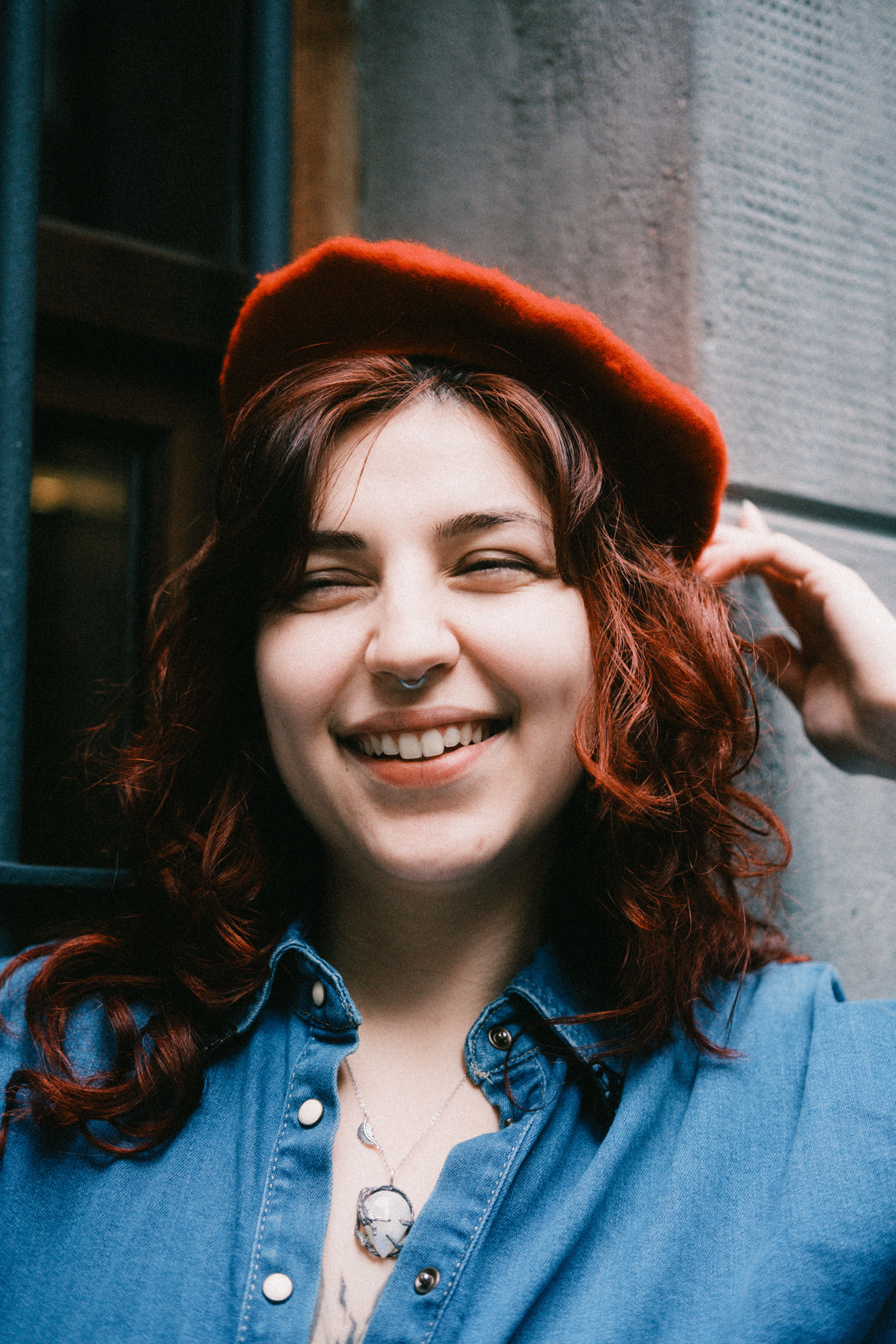 Happy woman with red beret and denim shirt, enjoying a moment in the city.