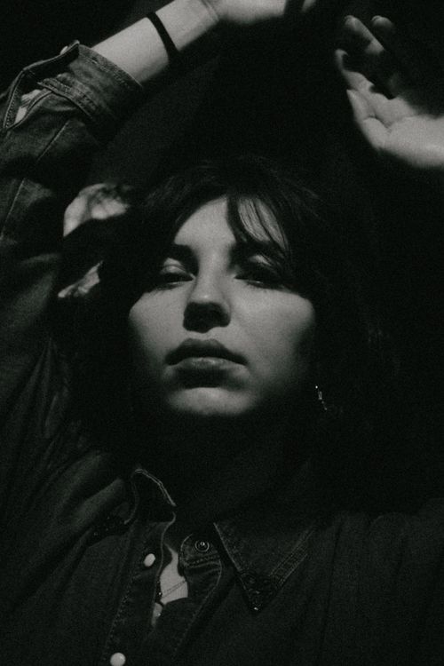 Free Dramatic black and white portrait of woman with arms raised in thoughtful expression. Stock Photo