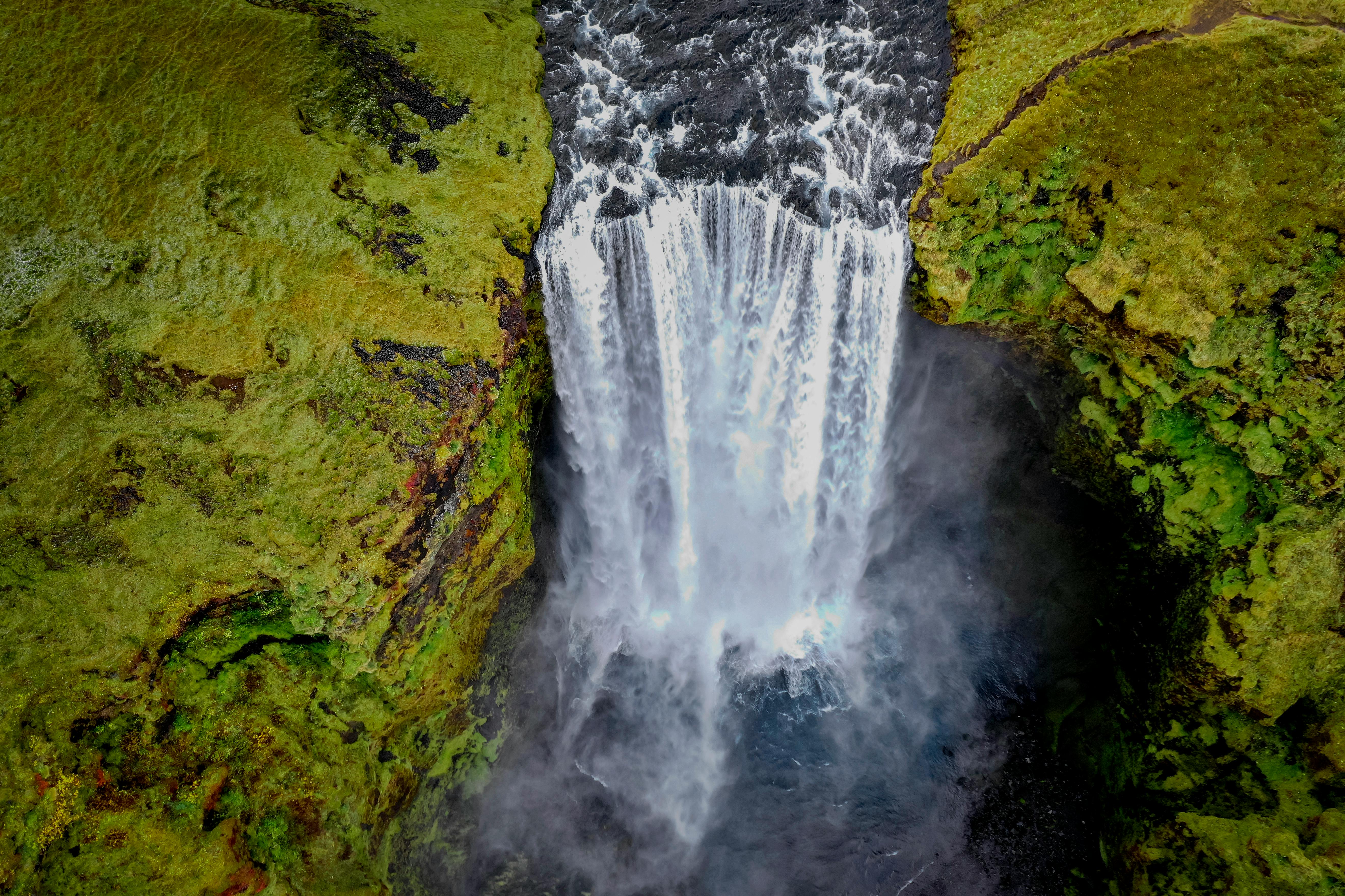 Breathtaking aerial shot of Skógafoss waterfall in Iceland, surrounded by lush green moss.