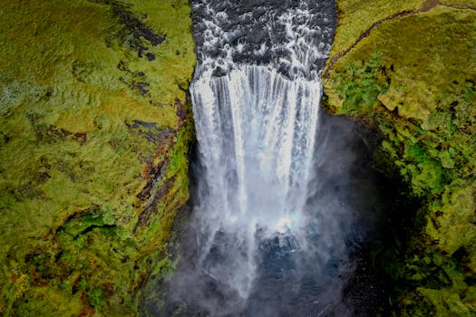 Breathtaking aerial shot of Skógafoss waterfall in Iceland, surrounded by lush green moss.