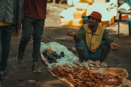 A street vendor sells fresh produce at an outdoor market, engaging with customers.