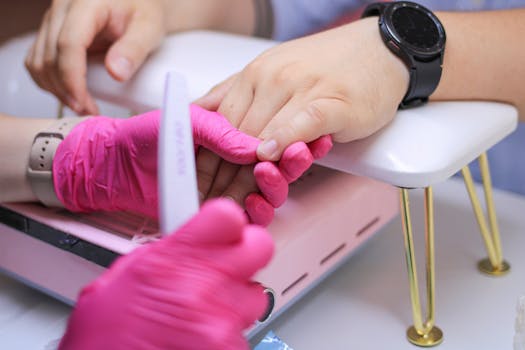 Close-up of hands receiving a manicure in a professional nail salon, highlighting attention to detail and hygiene.