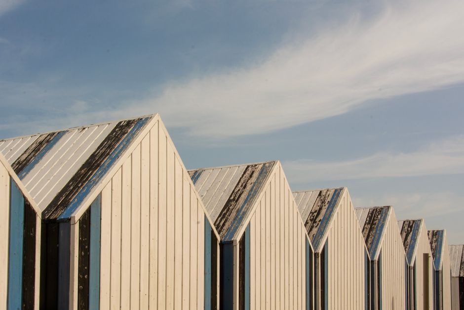 Row of coastal beach huts in Yport, Normandy against a clear sky.