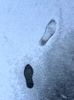 Two distinct footprints contrast on snowy surface, illustrating a winter journey.