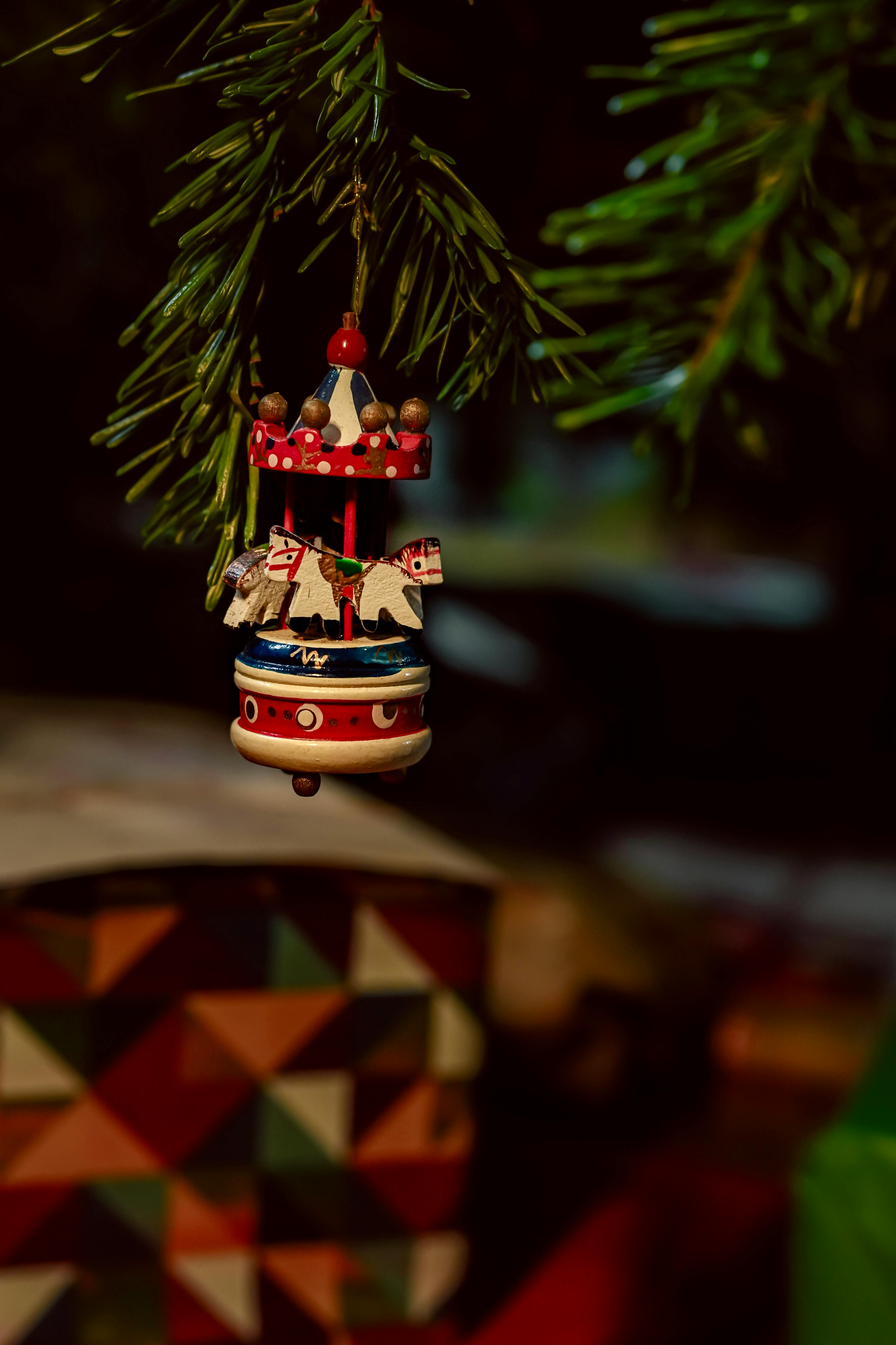 Close-up of a decorative Christmas ornament hanging on a pine tree branch with festive ambiance.