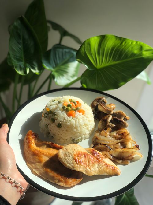 Free Plate of grilled chicken with vegetable rice and sautéed mushrooms, garnished with greens. Stock Photo