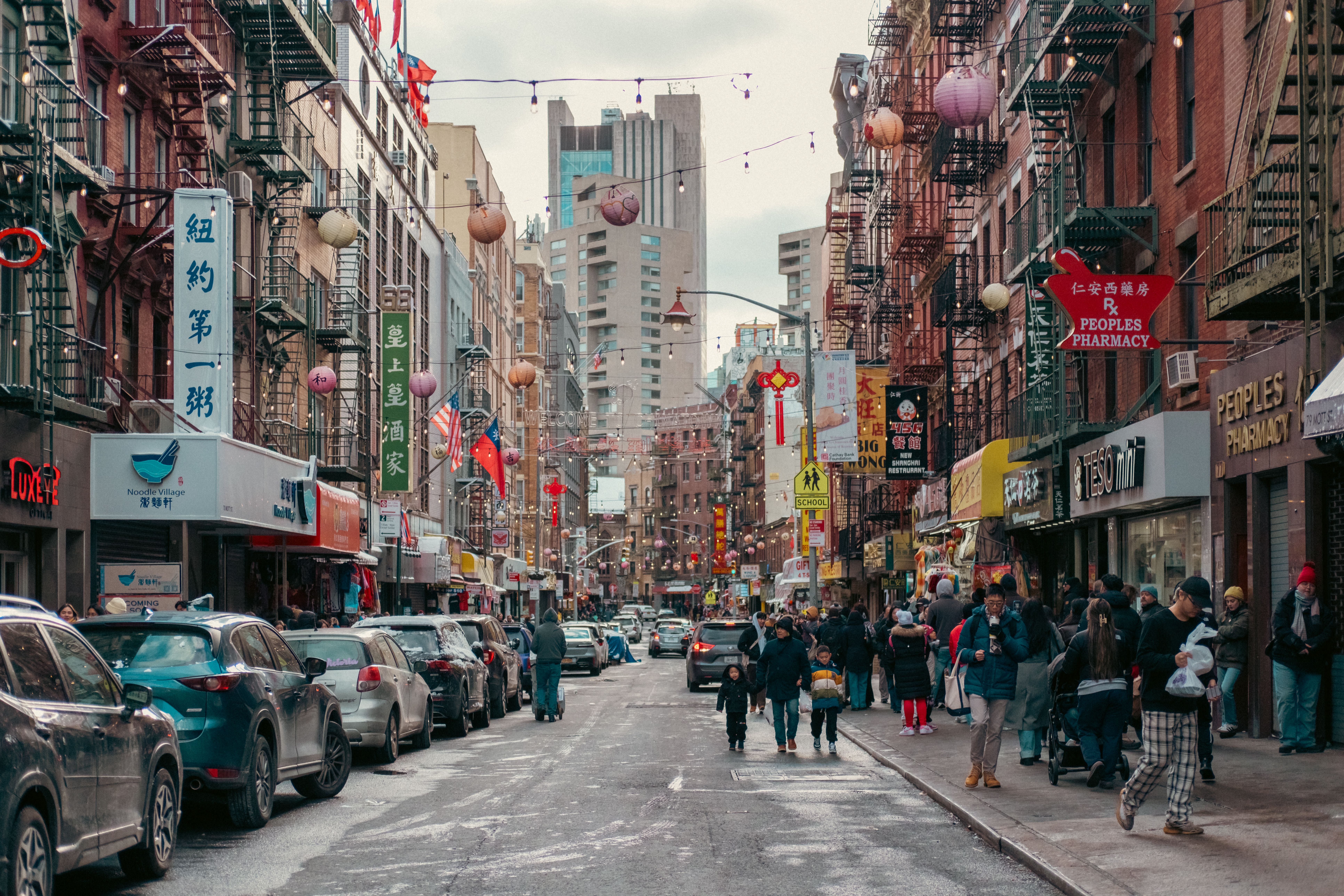 Vibrant street scene in Chinatown, NYC featuring lanterns, storefronts, and diverse crowds