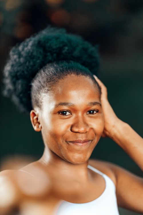 Free Portrait of a happy young woman with natural curly hair and a warm smile. Stock Photo