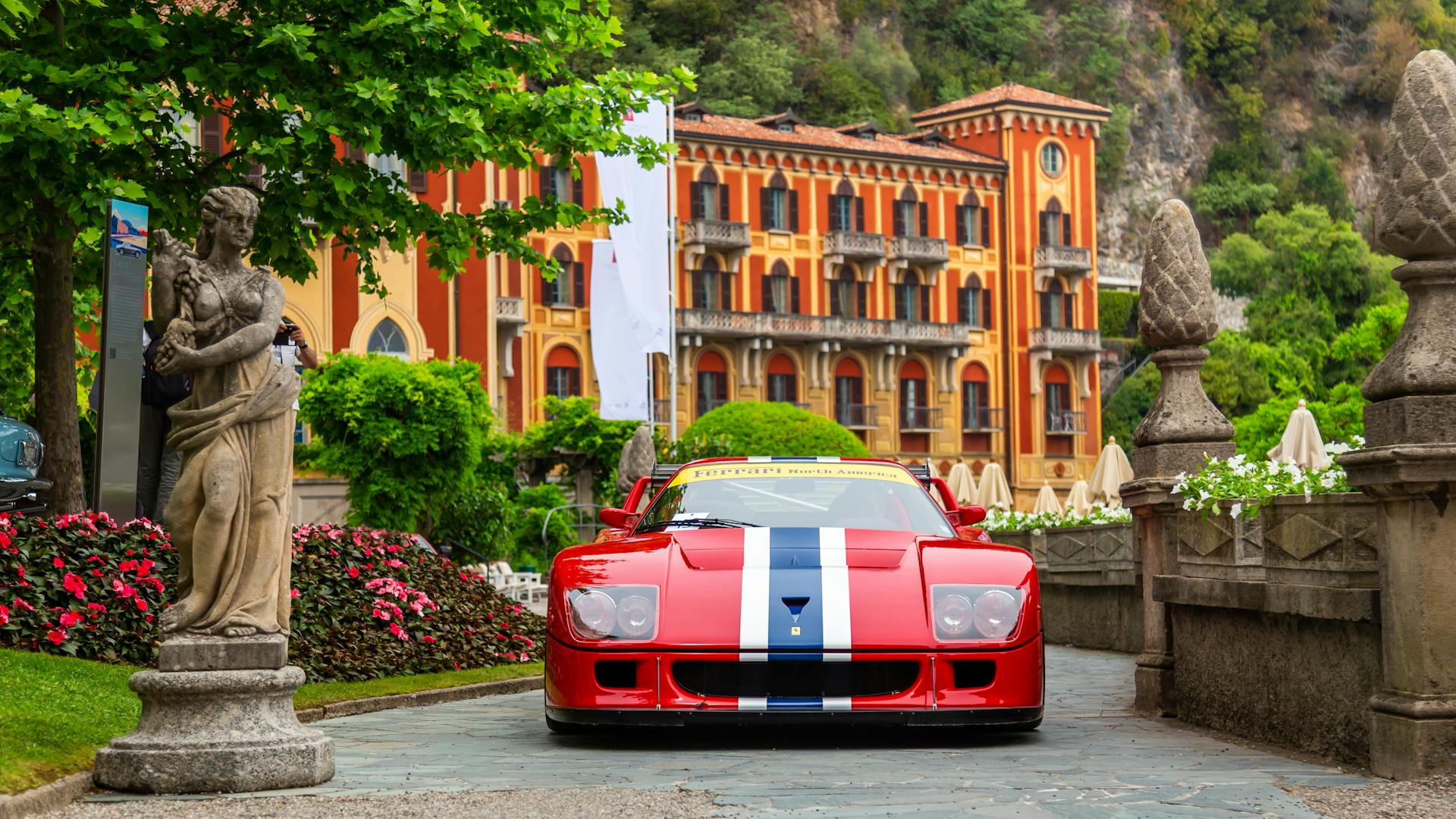 A vintage red sports car parked elegantly in front of an Italian villa, showcasing classic design.