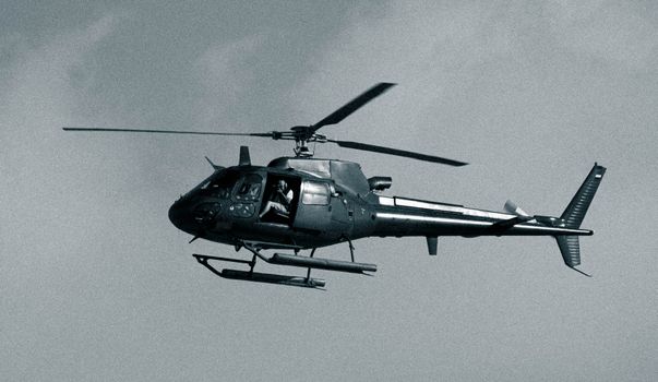 A black and white photo of a helicopter in flight, capturing the essence of aviation.