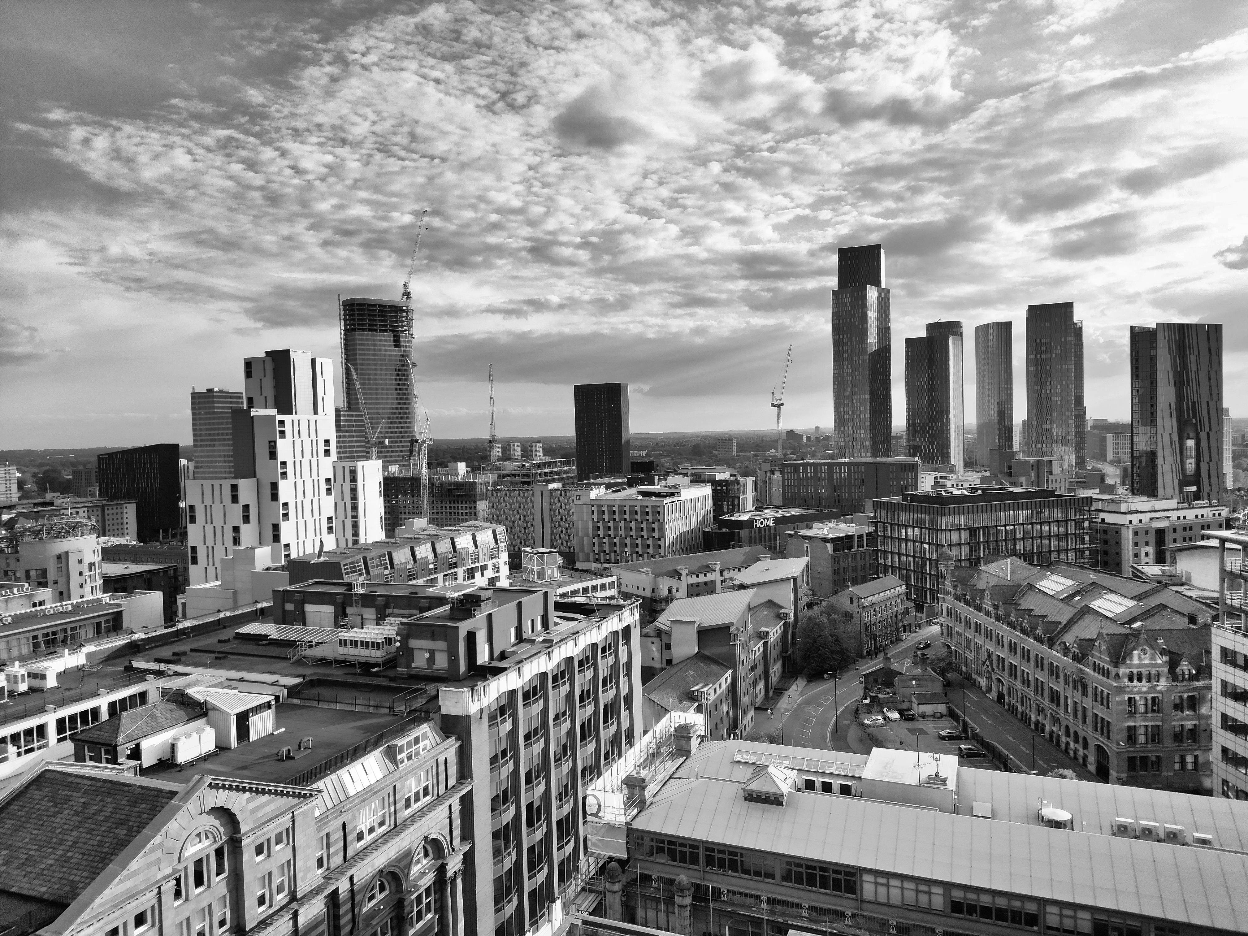 A monochrome cityscape showcasing the modern architecture of Manchester, UK under a dramatic sky.