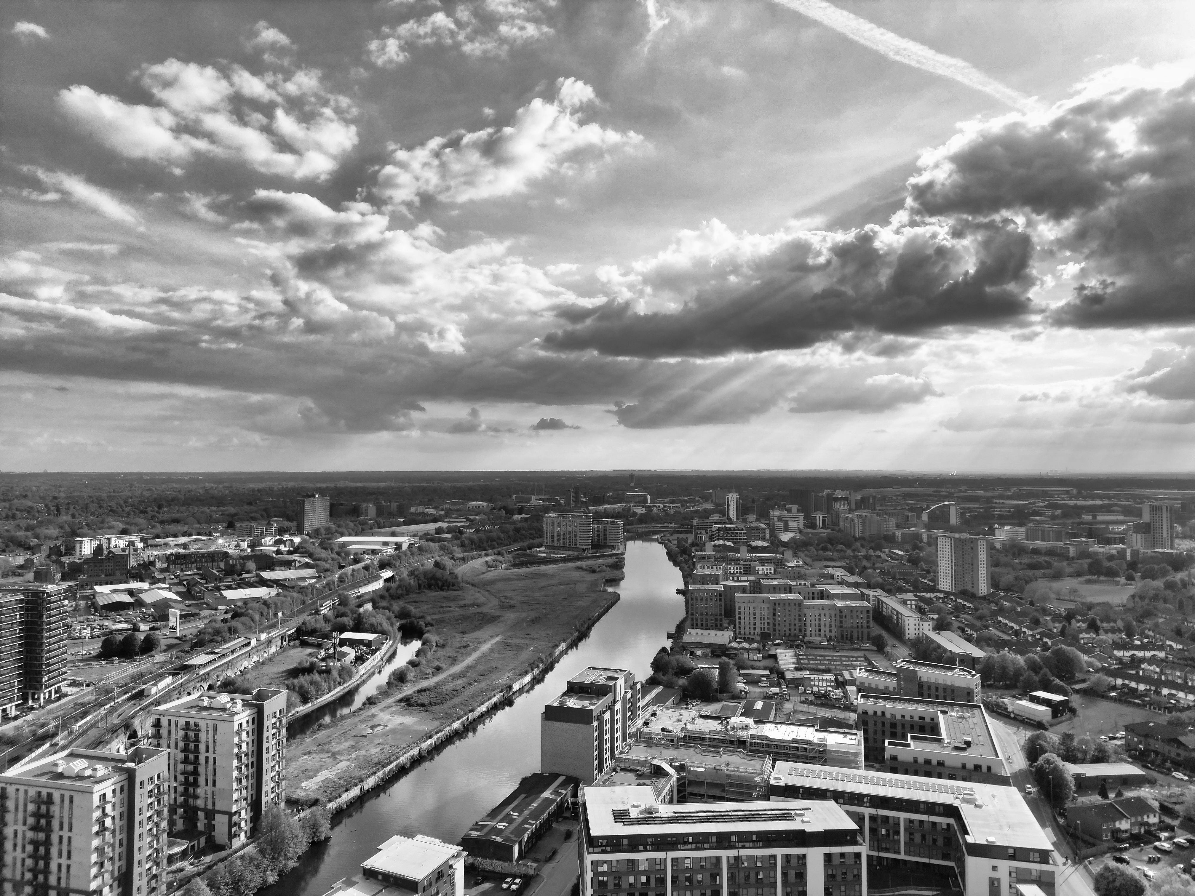 A dramatic black and white aerial view of Salford Quays, Manchester, with dynamic cloud cover.