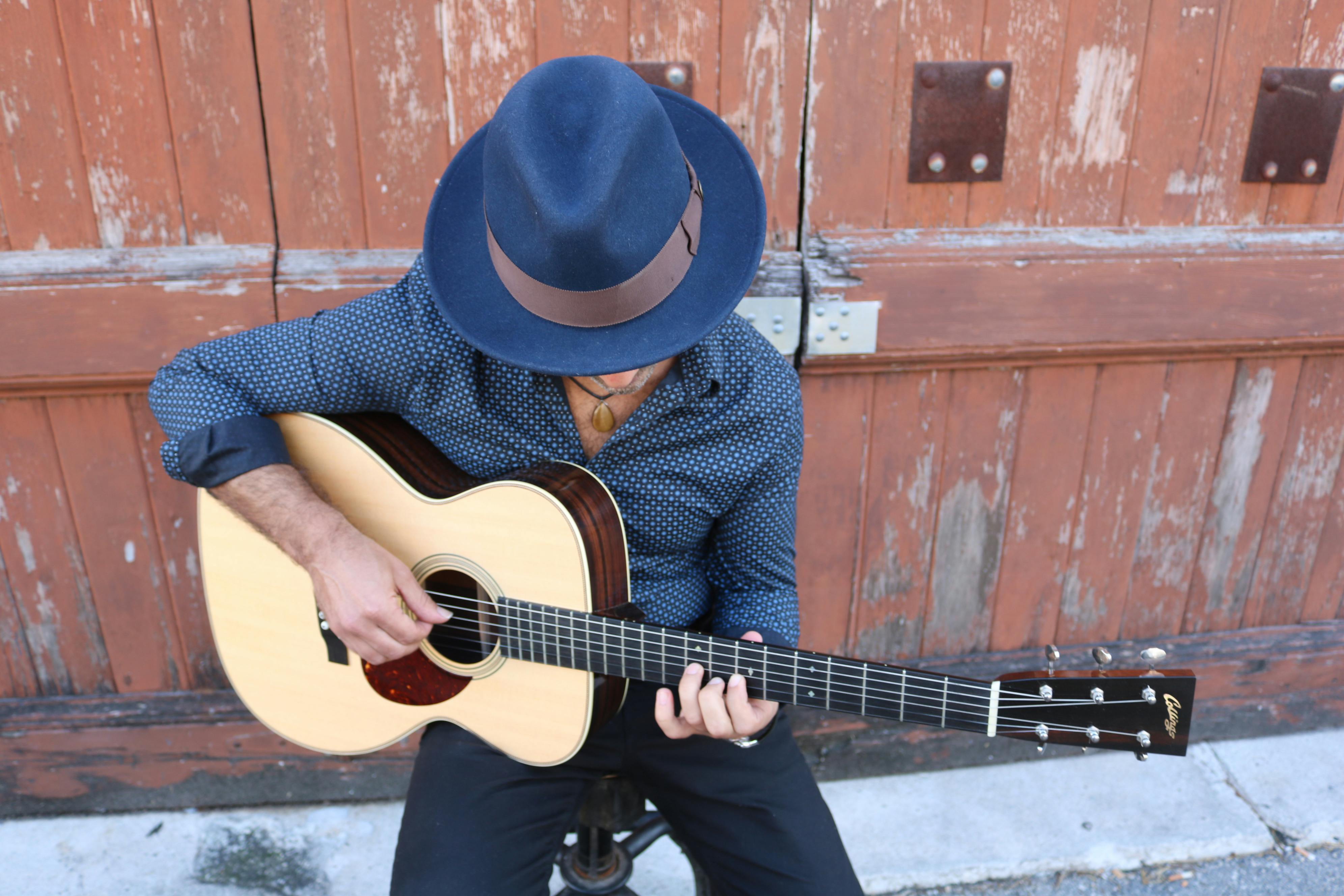 Top view of a musician playing an acoustic guitar with a rustic backdrop.