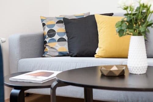 無料 3つの枕が付いているソファーの横のコーヒーテーブルの目玉 写真素材